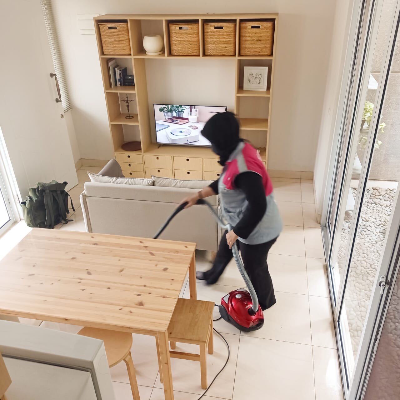 penyedia jasa daily cleaning Sejasa sedang membersihkan lantai dengan menggunakan vacuum cleaner