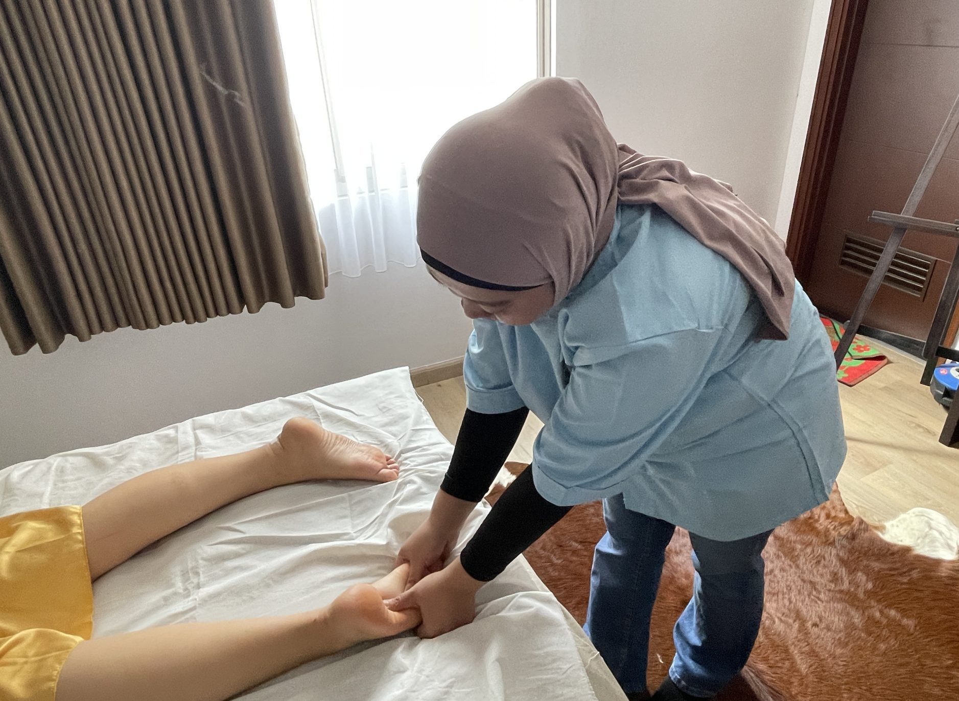 terapis Sejasa sedang memberikan pijat refleksi pada bagian telapak kaki