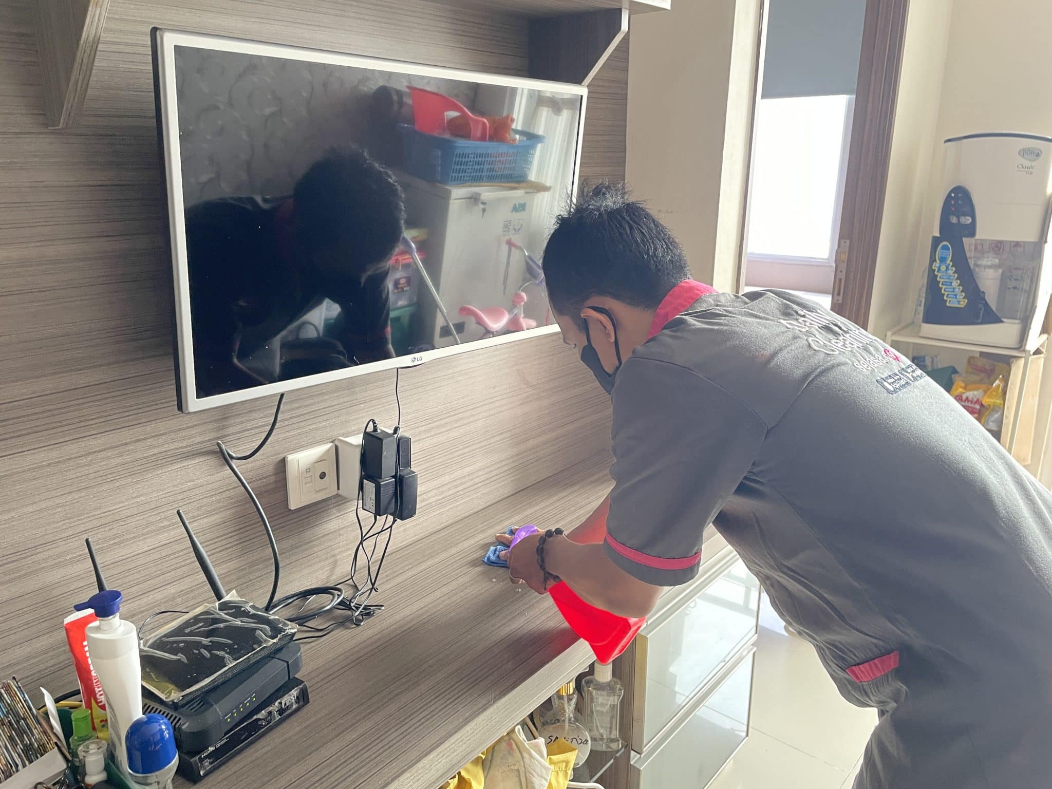 paket cleaning mitra cleaning Sejasa sedang melakukan pembersihan pada bagian rak TV