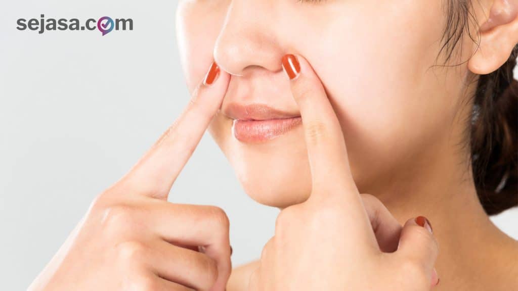 seorang wanita sedang melakukan pijatan di area hidungnya
