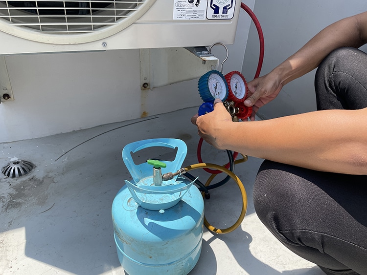 teknisi sedang melakukan pengisian freon AC