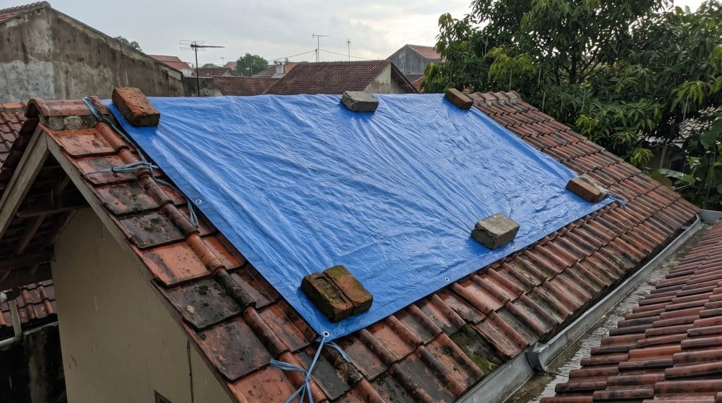 terpal biru menutupi kebocoran atap